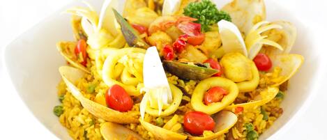 Un plato de paella de mariscos con almejas, camarones y verduras.