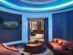 Un hall d’hôtel moderne avec un espace salon aux lignes courbes, un téléviseur à écran plat et une vue sur la salle à manger.