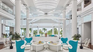 A spacious lobby with high ceilings, large windows, and a central seating area with white and blue chairs. - Mövenpick Hotel Mactan Island Cebu (Lapu-Lapu)