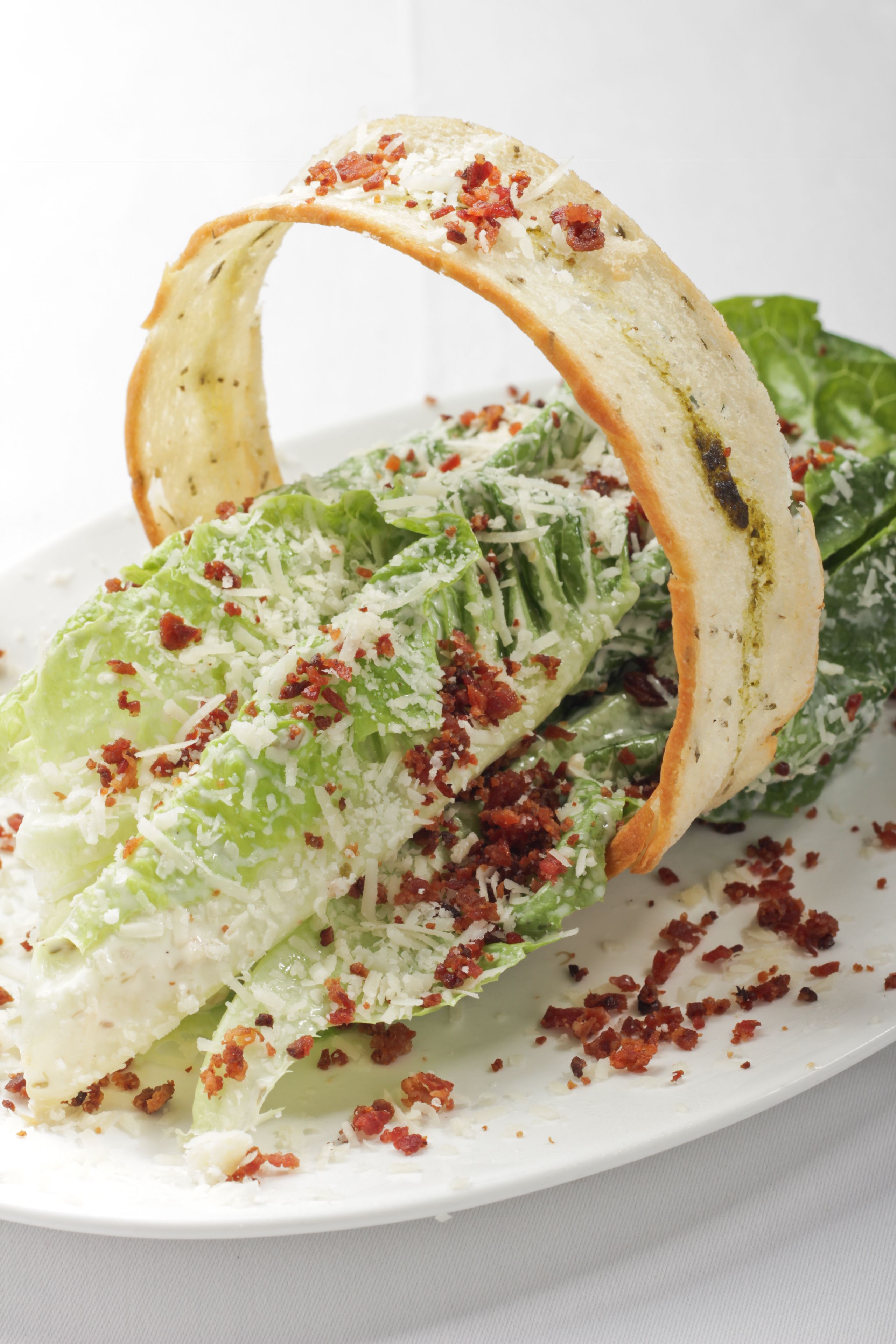 A plate with a salad, including lettuce and croutons, garnished with cheese and bacon bits.