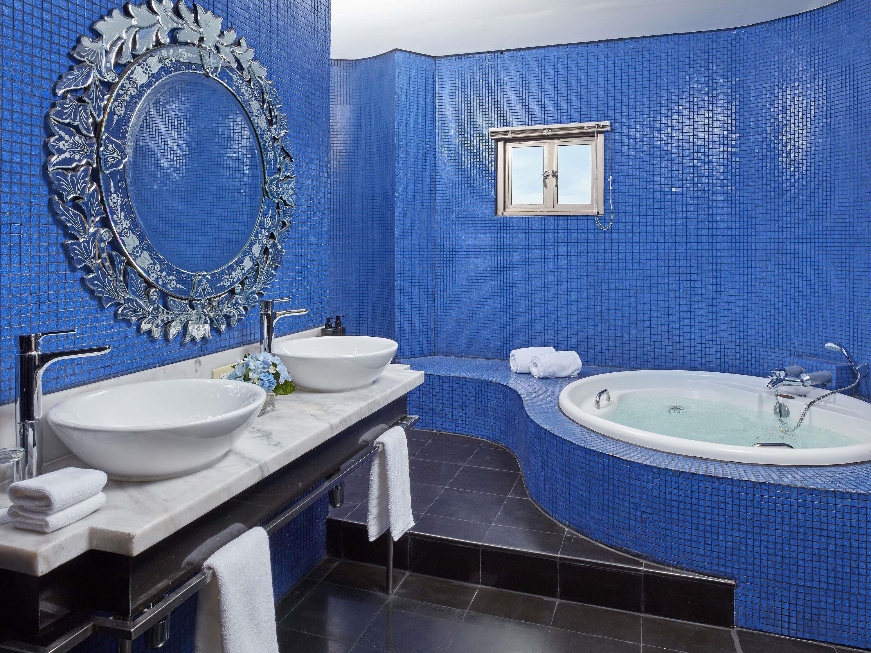A bathroom with two sinks, a bathtub, and a mirror with an ornate frame.