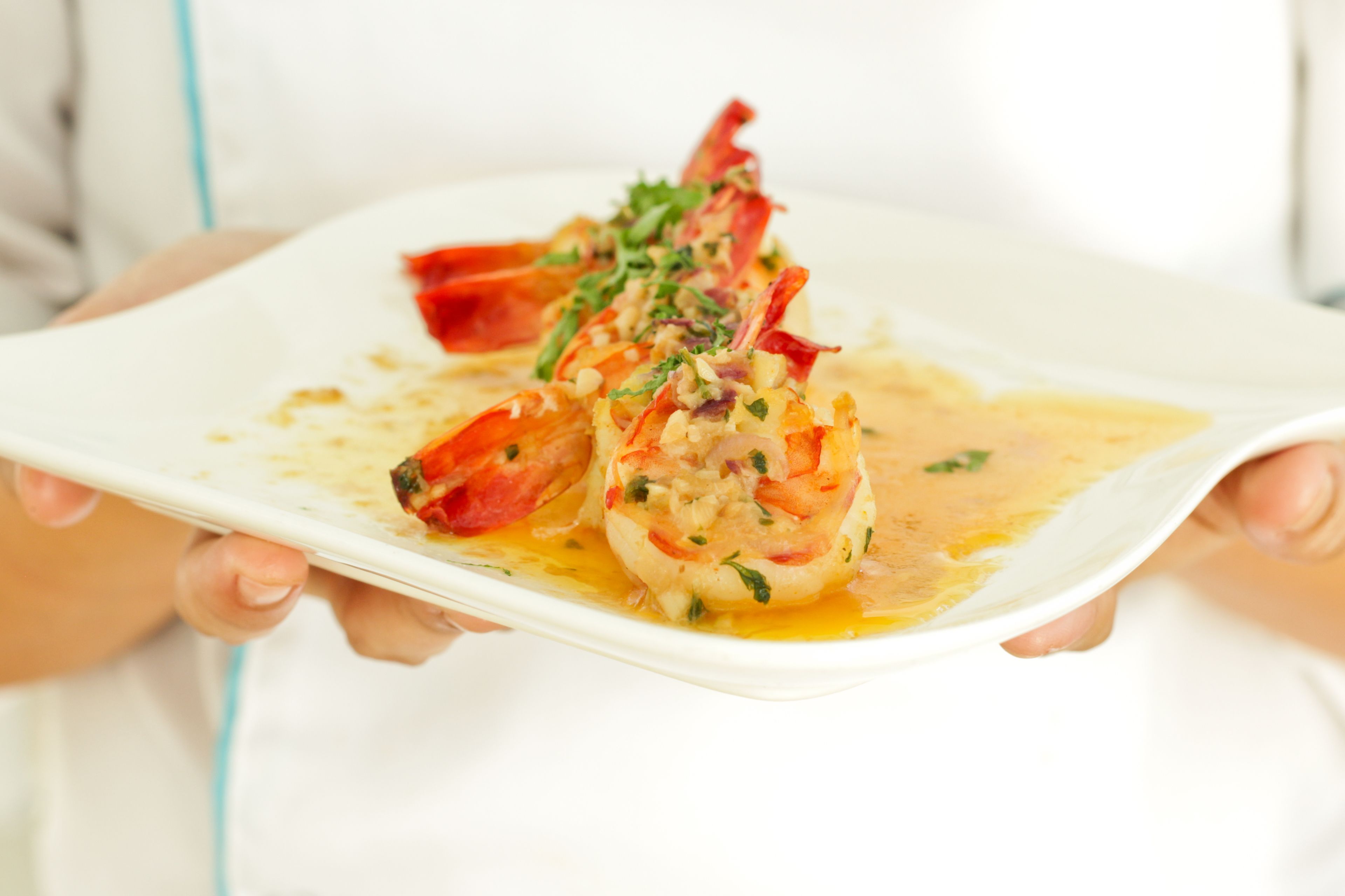 A person holding a white plate with a lobster dish.