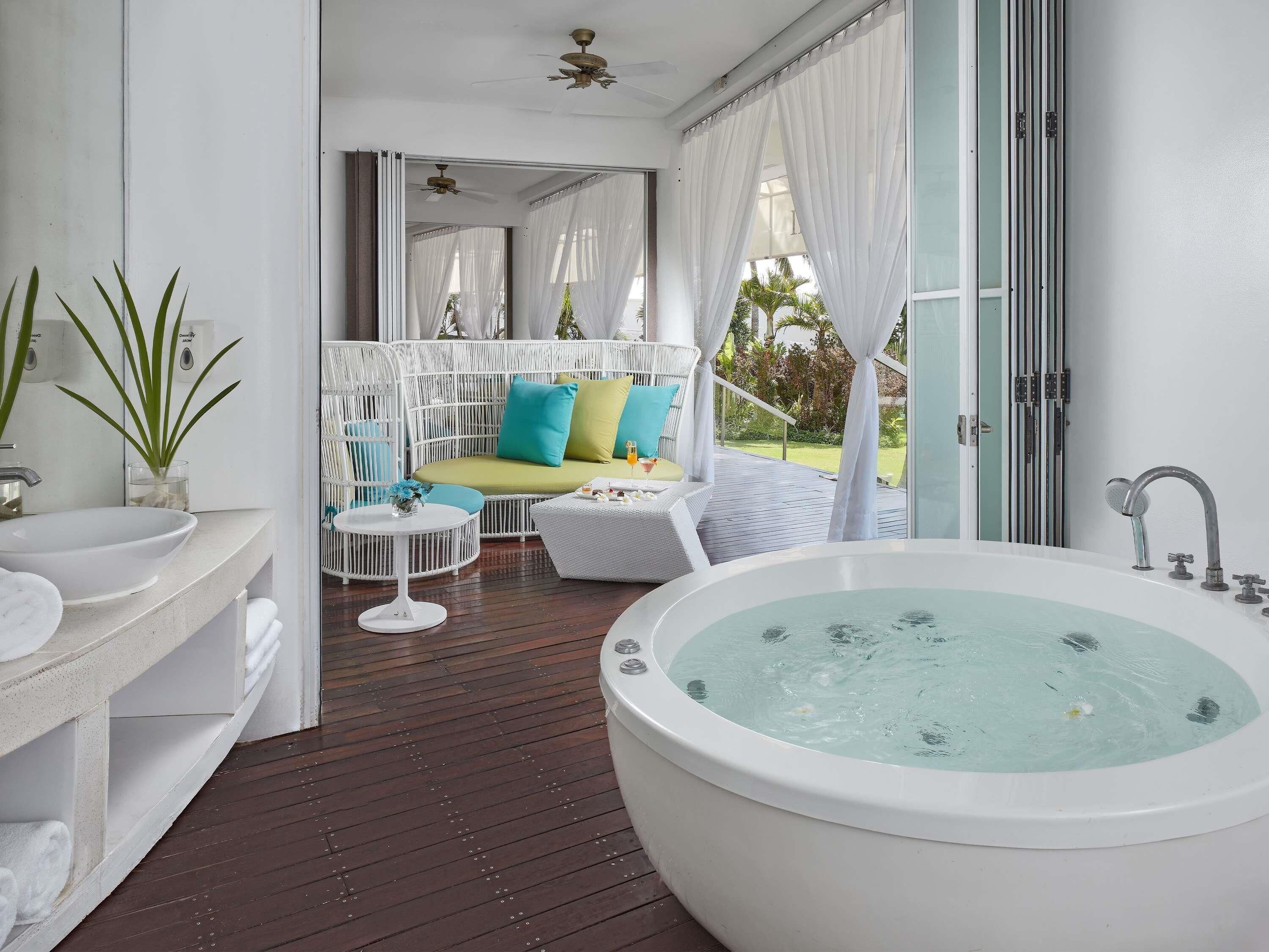A bathroom with a large bathtub, a white sink, and a round table with a vase.