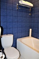 Um banheiro com vaso sanitário branco, banheira branca e um porta-toalhas acima da banheira.