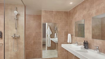 Un baño moderno con ducha a nivel, un espejo grande y un tocador blanco con lavamanos.