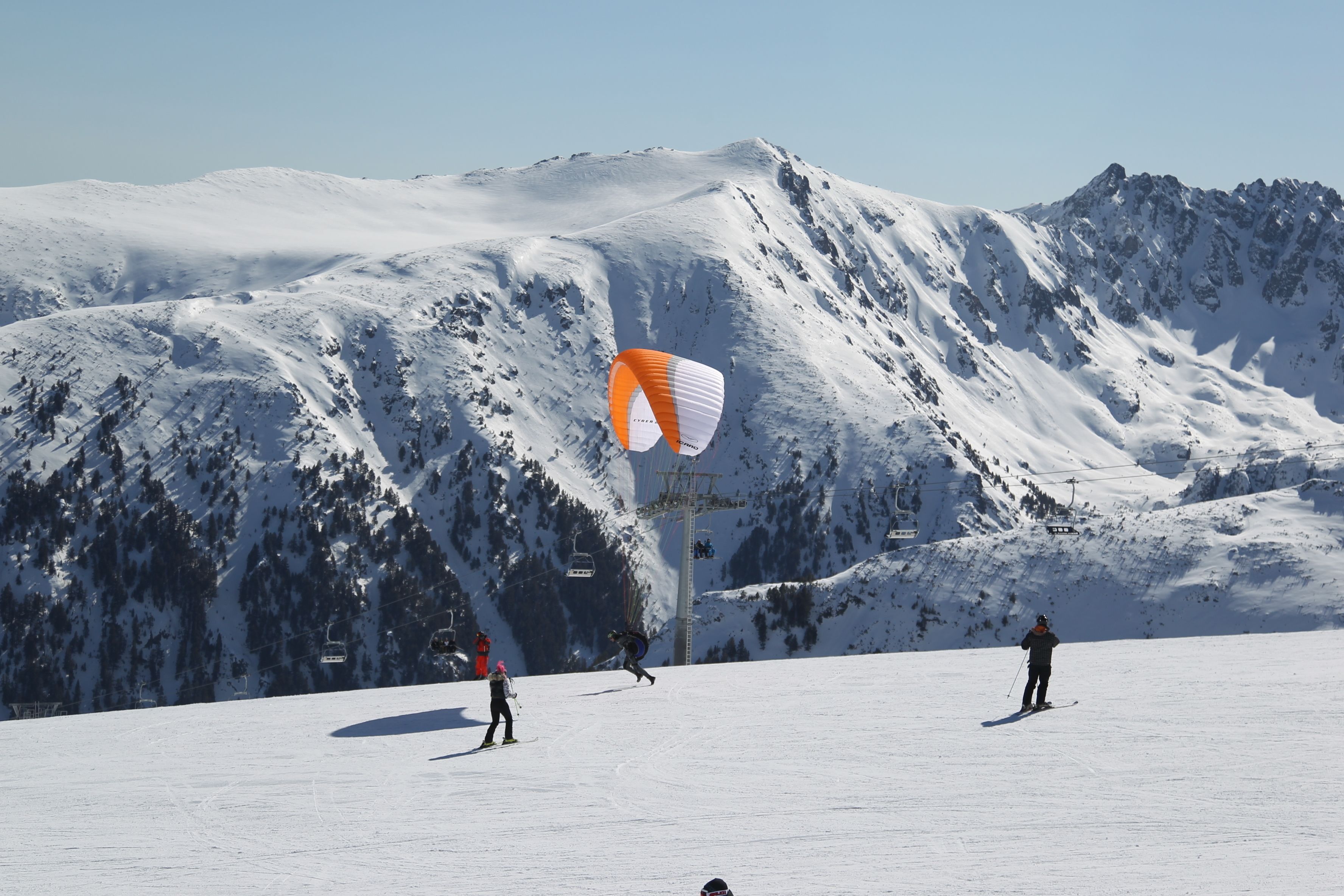 A snowy mountain landscape with skiers and a chairlift.
