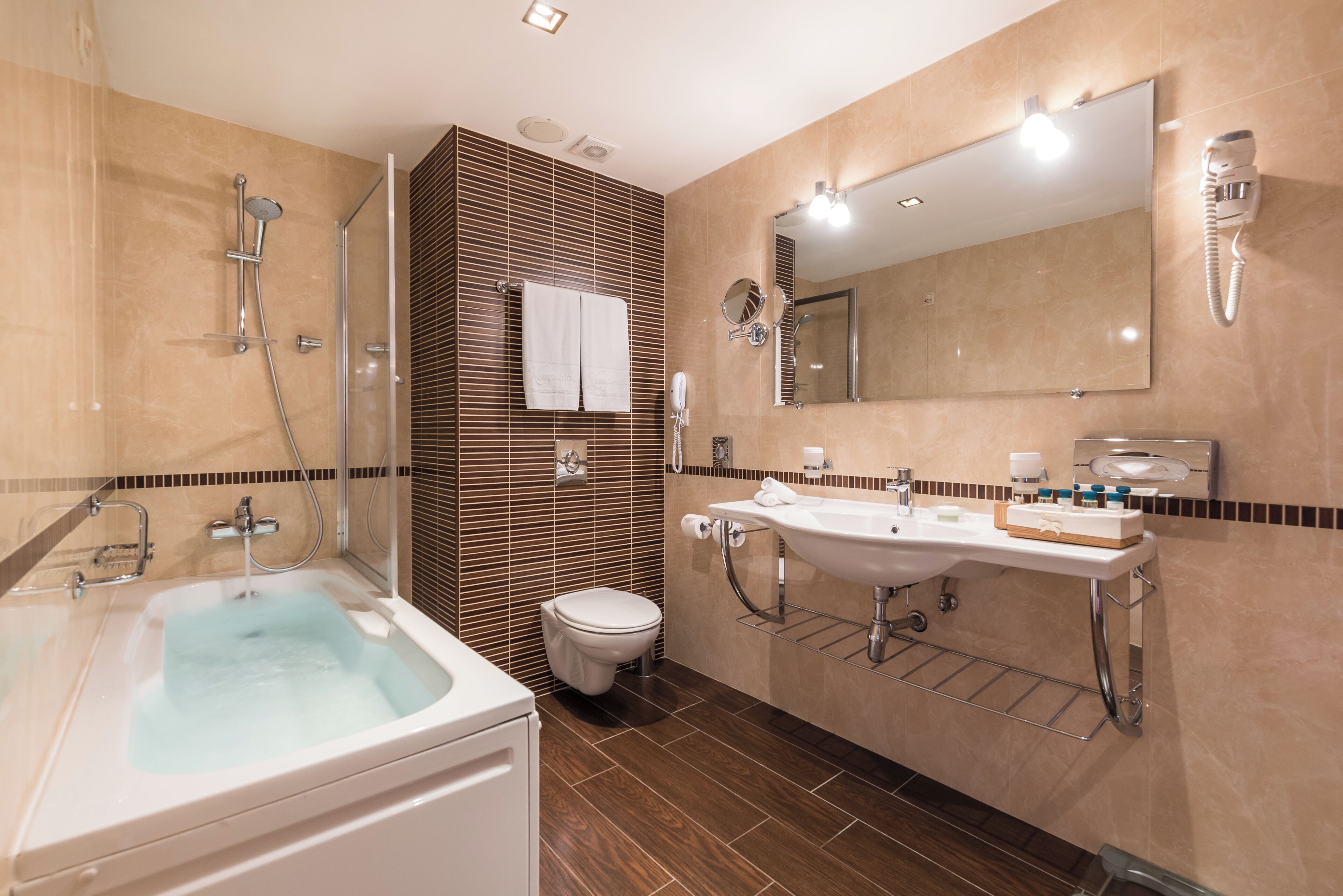 A modern bathroom with a bathtub, two sinks, a toilet, and a shower.