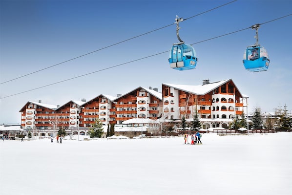 A multi-story hotel with a ski lift in the background. - Kempinski Hotel Grand Arena (Bansko)