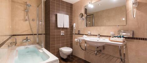 A modern bathroom with a bathtub, two sinks, a toilet, and a shower.