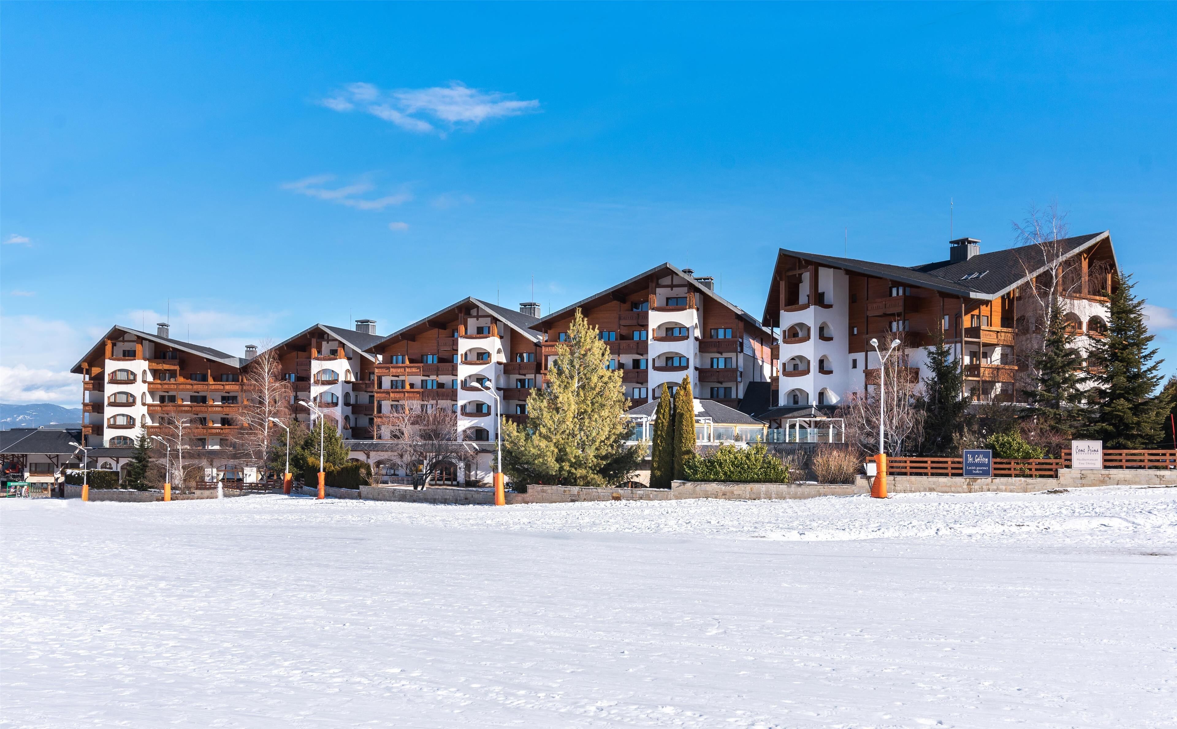 Un hotel de varios pisos con un paisaje de estación de esquí, con balcones y un suelo cubierto de nieve.