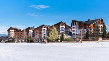 Un hotel de varios pisos con un paisaje de estación de esquí, con balcones y un suelo cubierto de nieve.