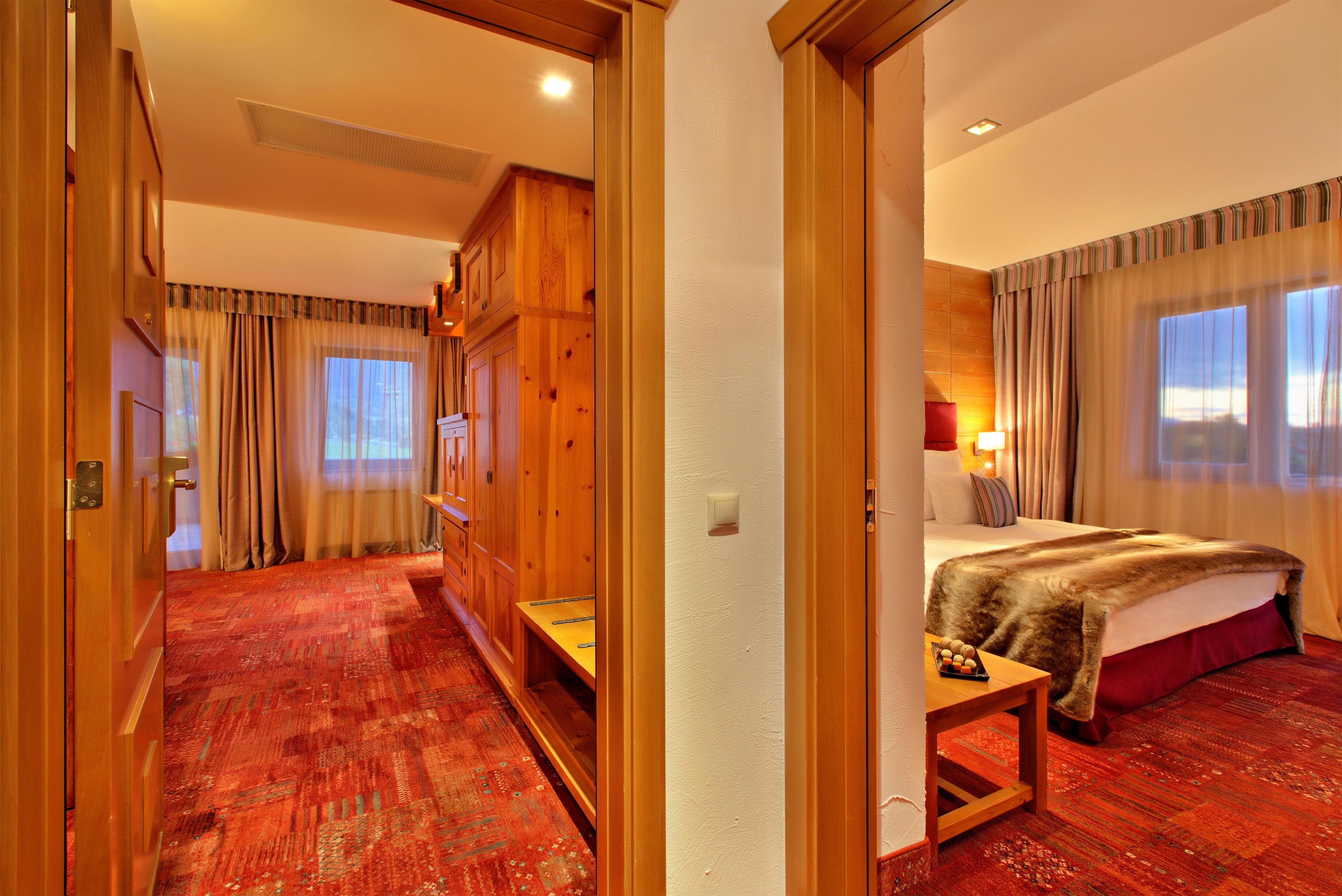 Habitación de hotel con un armario de madera, una cama con colcha roja y vistas al exterior a través de la ventana.