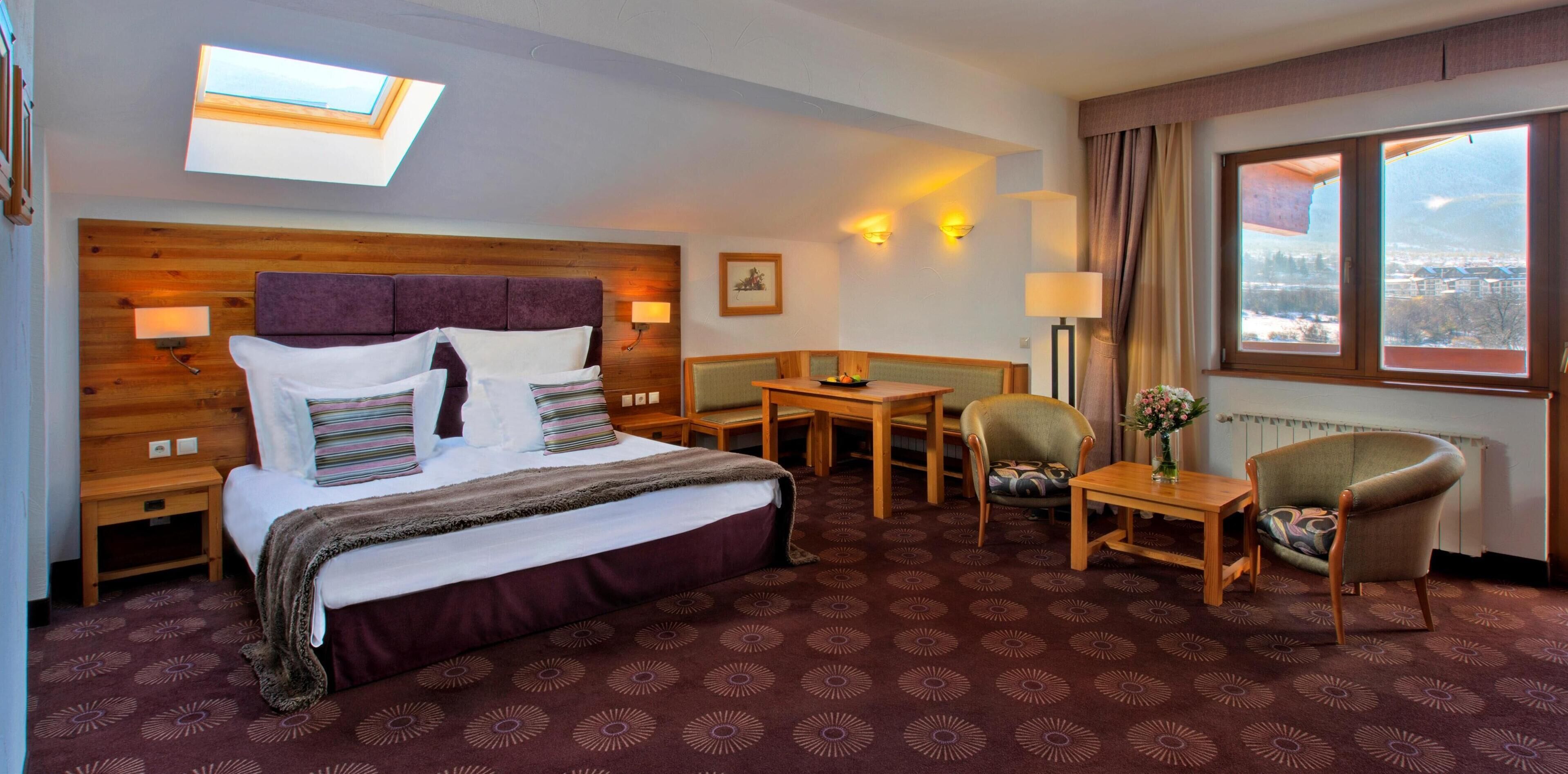 Een hotelkamer met een bed, een bureau, een stoel, een lamp en uitzicht op buiten.