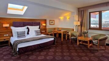Een hotelkamer met een bed, een bureau, een stoel, een lamp en uitzicht op buiten.