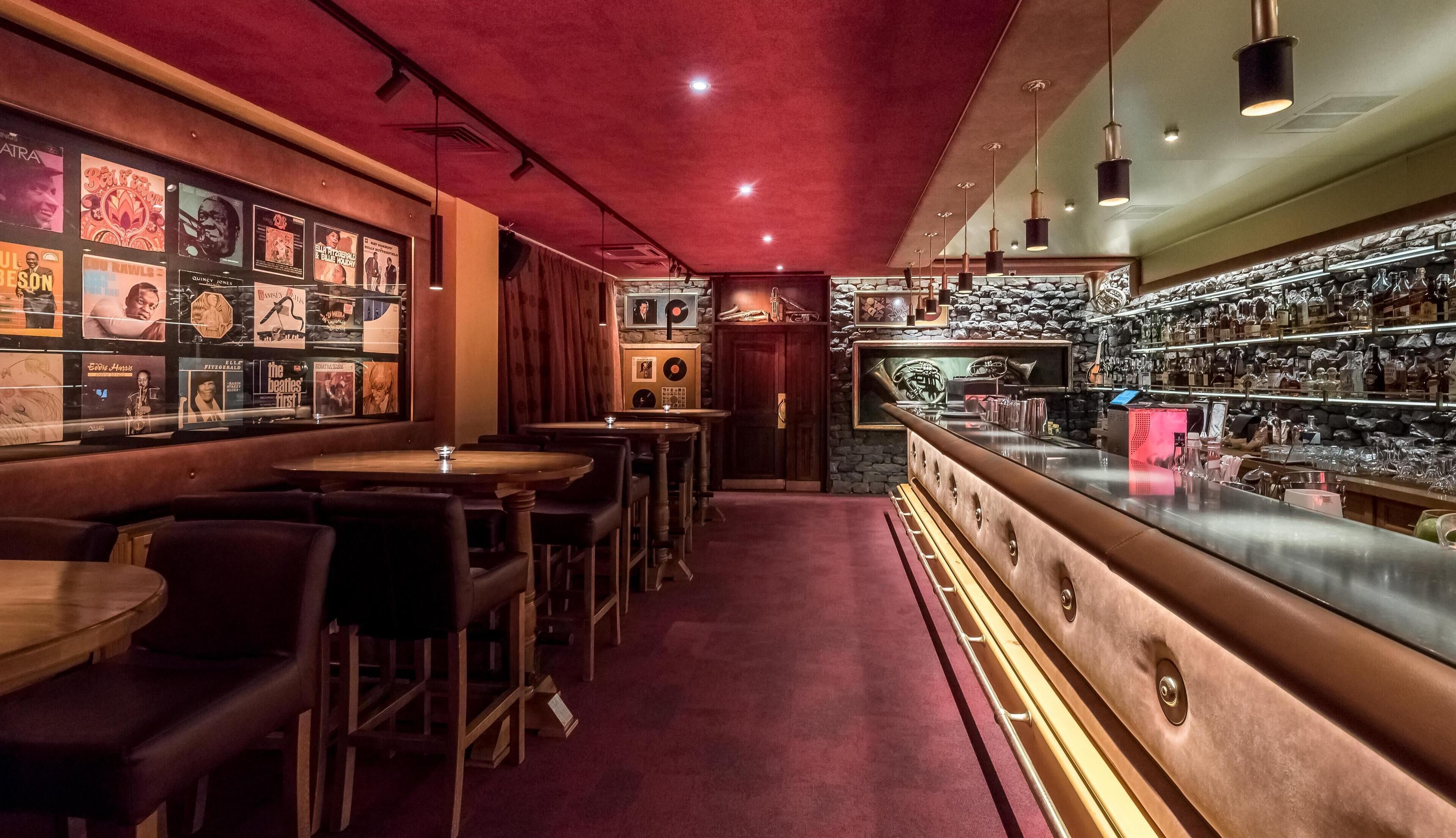 Un bar con techo rojo, mostrador de bar de madera y varios carteles en la pared.