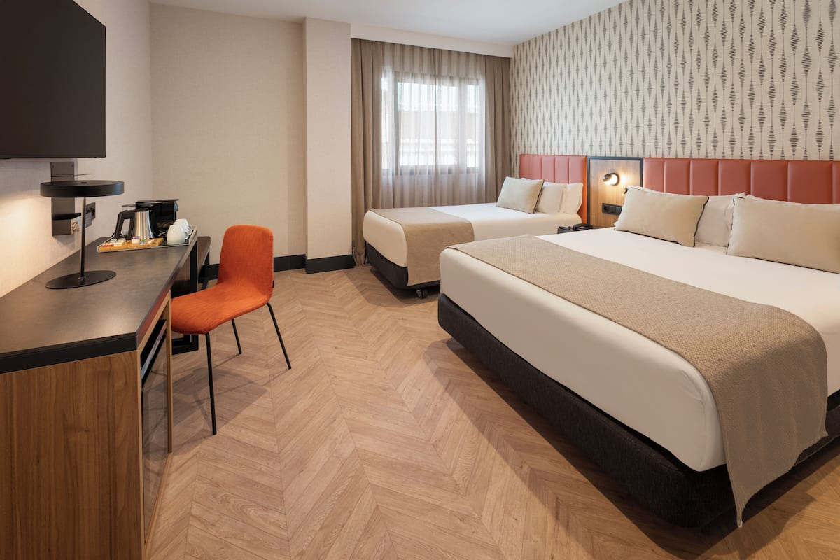 Una habitación de hotel con escritorio, dos camas, una silla y una televisión.