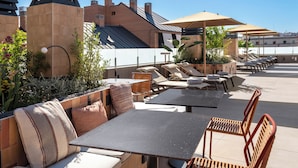 Eine Terrasse im Freien mit Sitzgelegenheiten, Tischen und Sonnenschirmen.