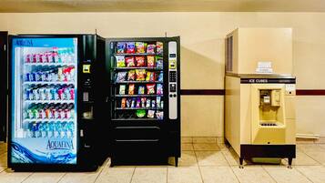 Tres máquinas expendedoras: un refrigerador de Coca-Cola, una máquina de aperitivos y un dispensador de hielo.