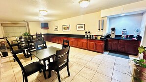 A dining area with tables and chairs, a kitchen with wooden cabinets, and a refrigerator.