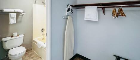 Un baño con inodoro, ducha y toallero con toallas colgadas.