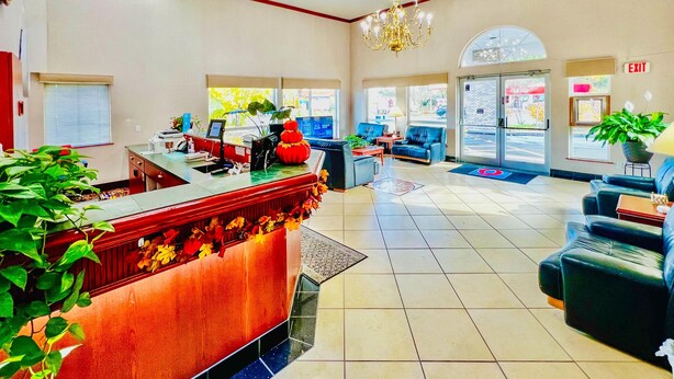 A hotel lobby with a reception desk, seating area, and large windows.