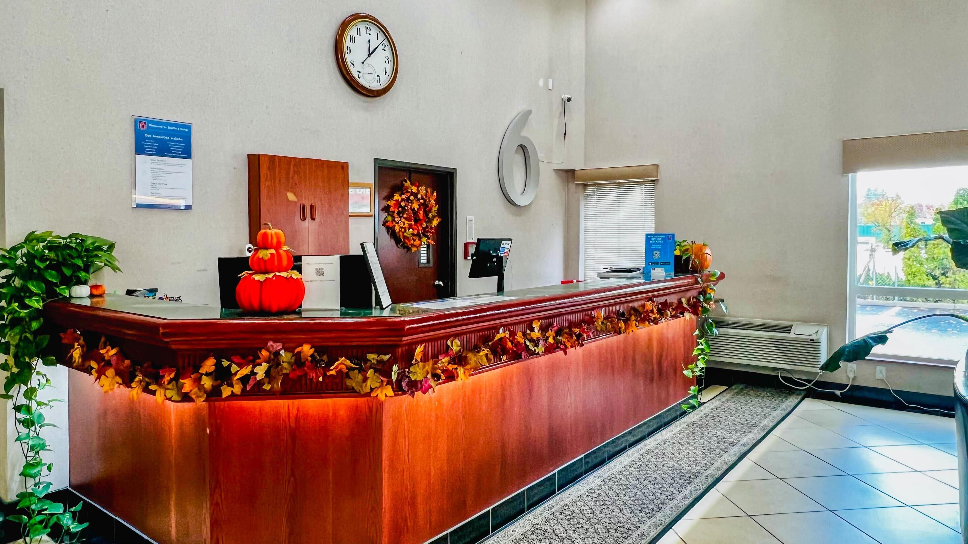 A reception desk with autumn leaves decoration, a clock, and a signboard.