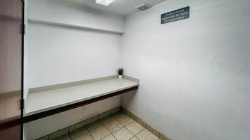 A clean, minimalistic bathroom with a white sink, a small potted plant, and a sign stating 'Studio 6 is not responsible for items left unattended.'
