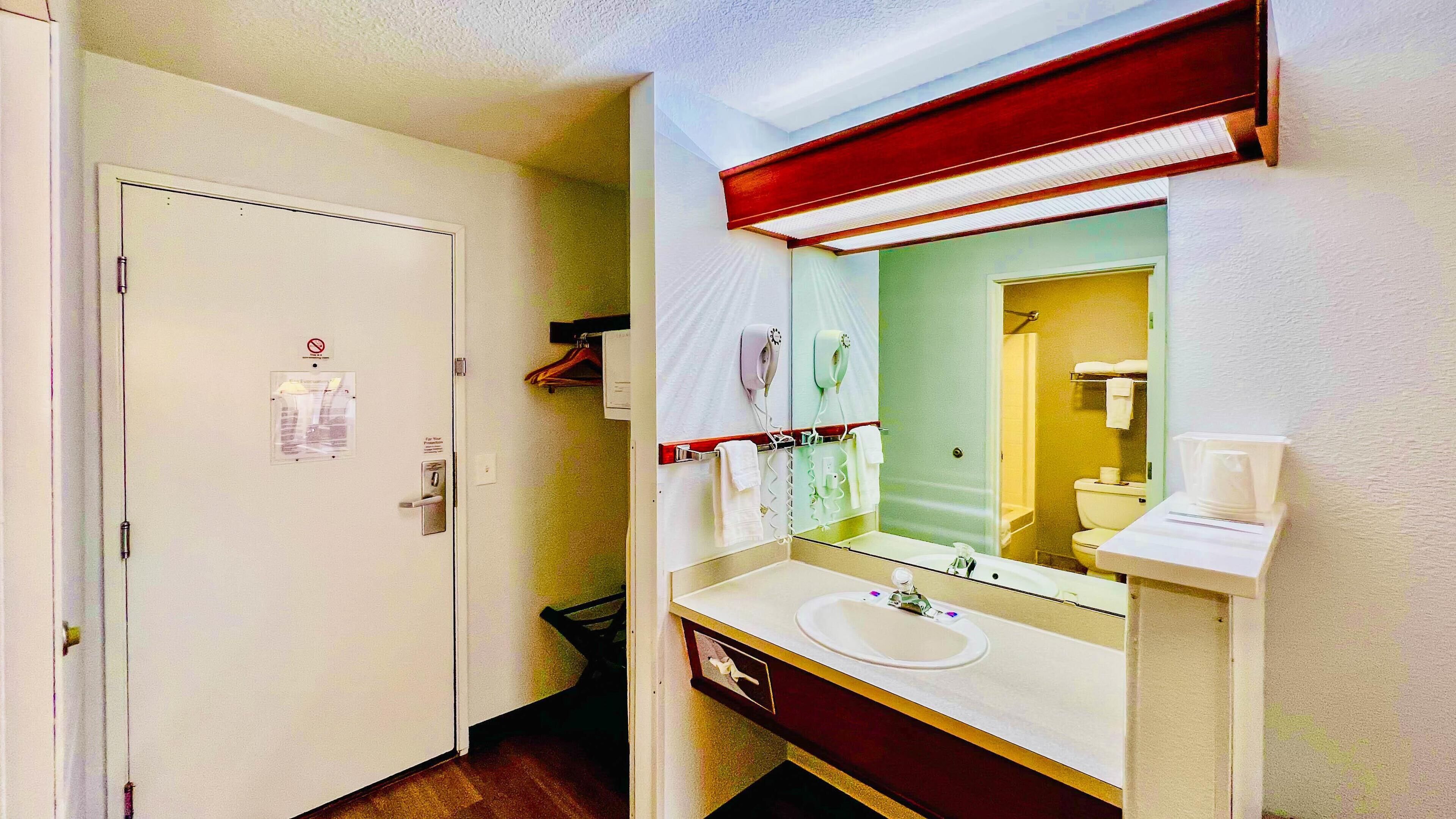 A hotel bathroom with a white sink, a mirror, and a shower area.