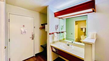 A hotel bathroom with a white sink, a mirror, and a shower area.