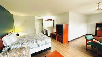 Una habitación de hotel con una cama, un escritorio, una silla, un televisor y un armario.