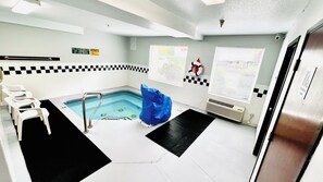 A spa room with a pool, a towel rack, and a caution sign. - Studio 6 Suites Portland OR- I-5 OHSU (Portland)