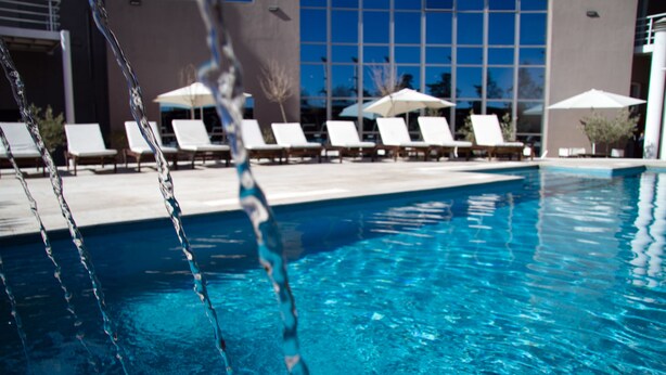 A swimming pool with clear water, surrounded by lounge chairs and umbrellas, indicating a resort setting.