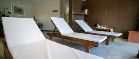 A room with two wooden lounge chairs and a small table with a plant.