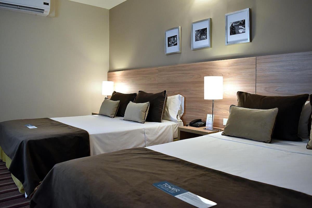 Une chambre d’hôtel avec deux lits, des lampes de chevet, une table de chevet et des tableaux encadrés au mur.