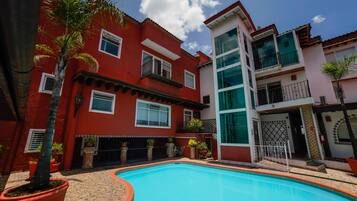 A residential building with a swimming pool, balconies, and potted plants.