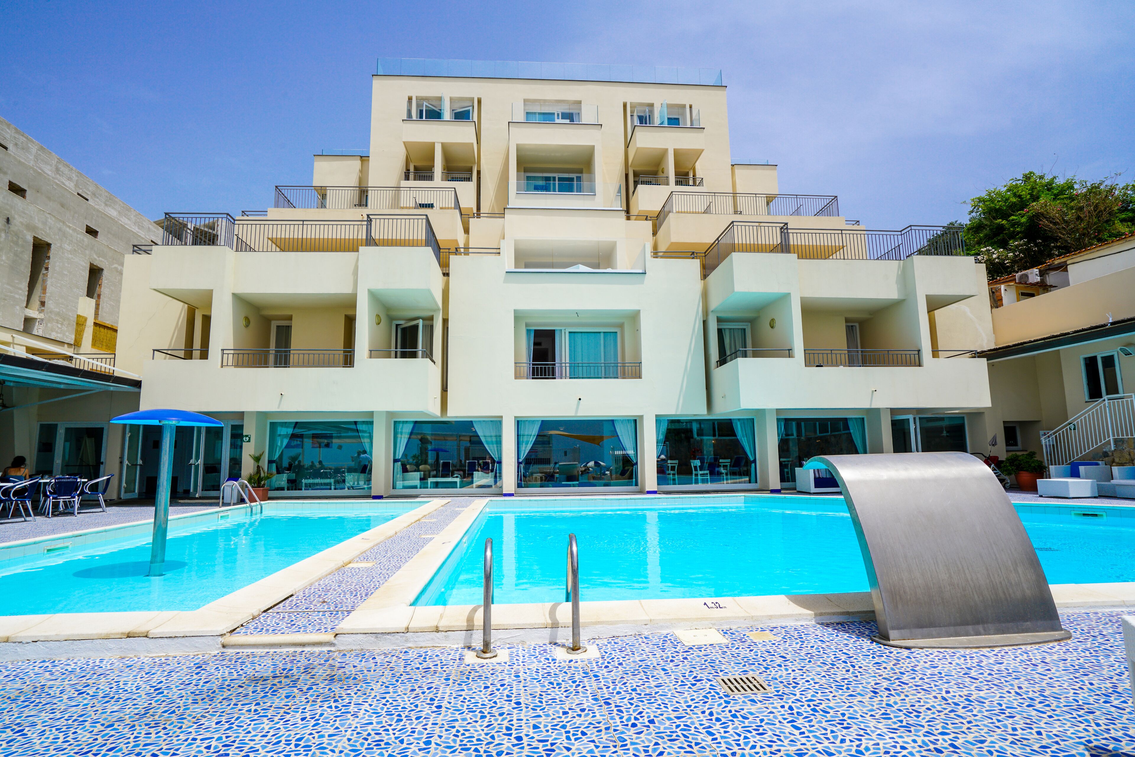 A hotel with a swimming pool, multiple balconies, and a tiled floor.