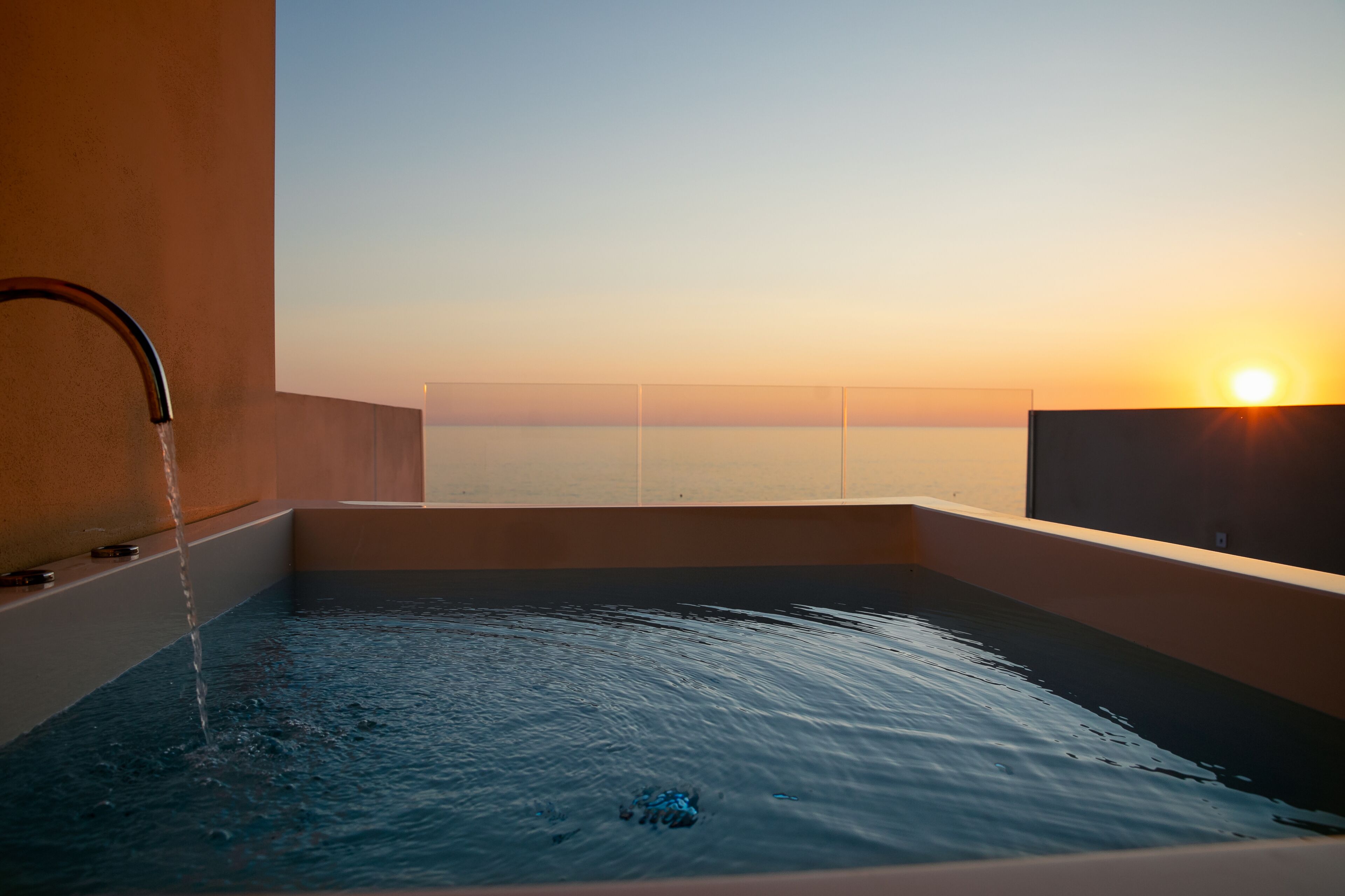 Una vasca idromassaggio con vista sul tramonto sull'oceano.