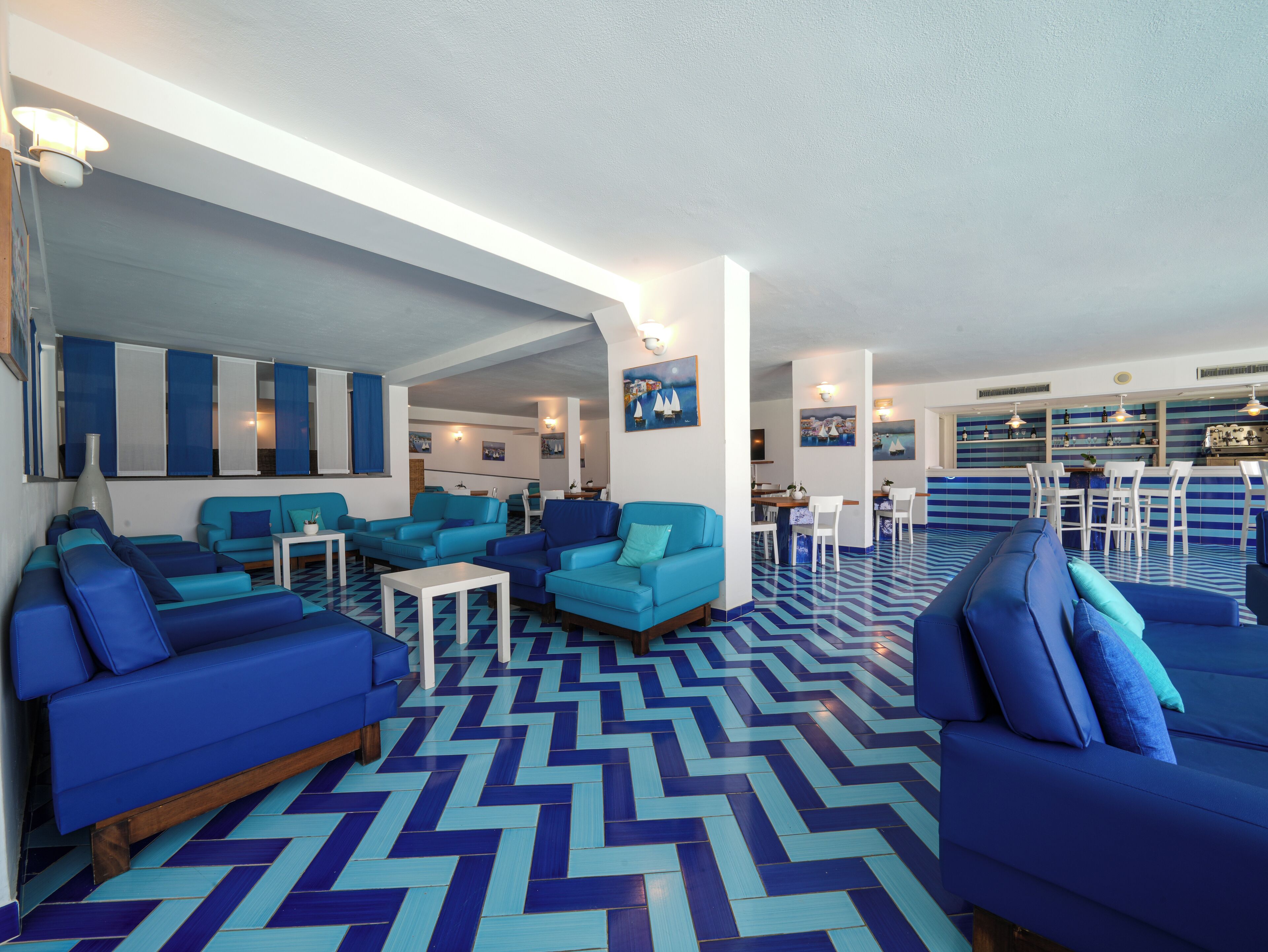 Een moderne hotel lobby met blauw-witte inrichting, een visgraatvloer en een bar.