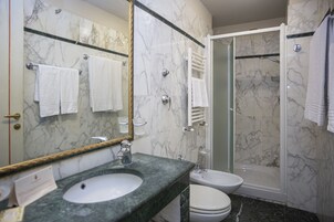 Un baño con lavamanos de mármol, inodoro, bidé y ducha a pie.