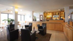 Uma área de bar moderna com balcão, banquetas e uma variedade de garrafas.