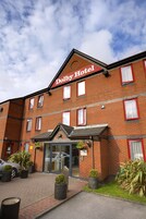 A hotel with a red-brick facade, a prominent "Dolby Hotel" sign, and a modern entrance with glass doors.