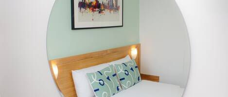 A circular room with a bed, a headboard, and a framed picture on the wall.
