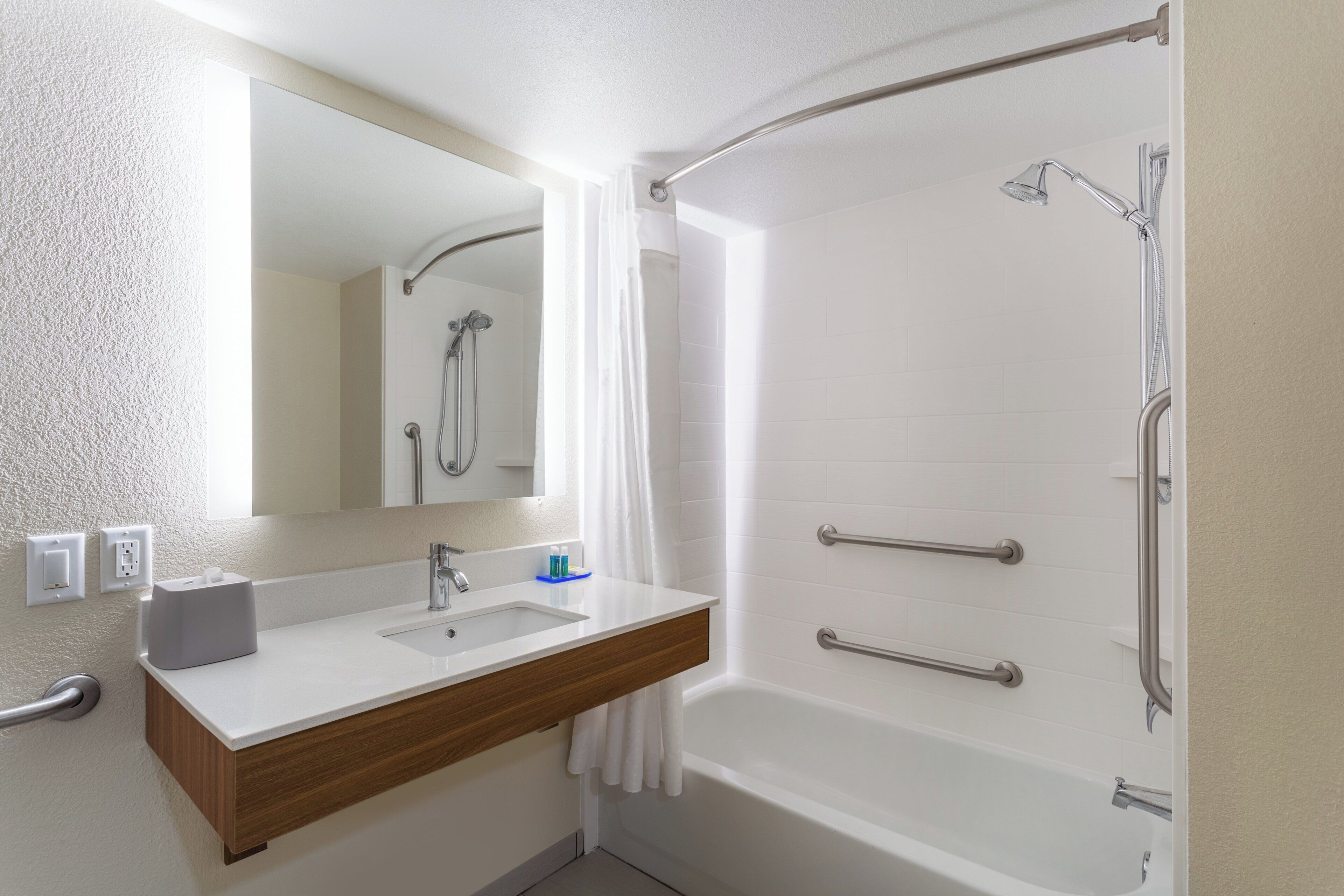 A bathroom with a white sink, mirror, and shower.