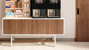 A modern kitchen with a wooden cabinet, a coffee machine, and storage shelves.