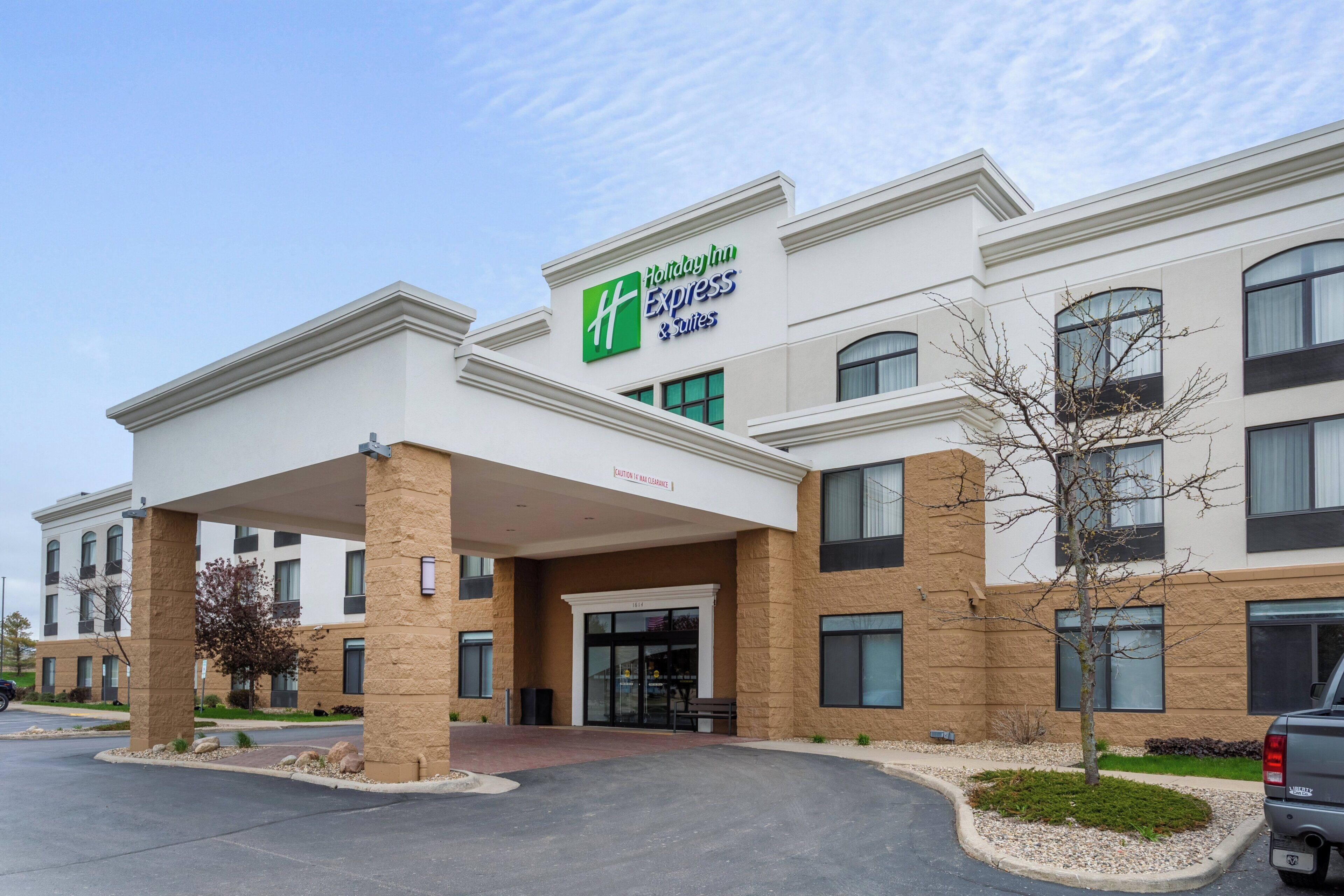 Un hotel Holiday Inn Express con entrada cubierta, varias ventanas y un estacionamiento.