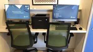 A workspace with two monitors, a desktop computer, and office chairs.