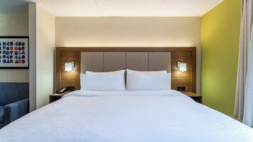 A hotel room with a large bed, two bedside tables, a headboard with built-in lighting, and a framed picture on the wall.