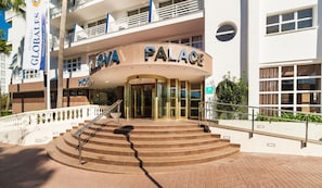 Una entrada de hotel con fachada curva, puerta de cristal y una escalera que conduce a la entrada.