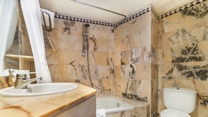 Un baño con lavamanos, bañera y retrete de mármol.