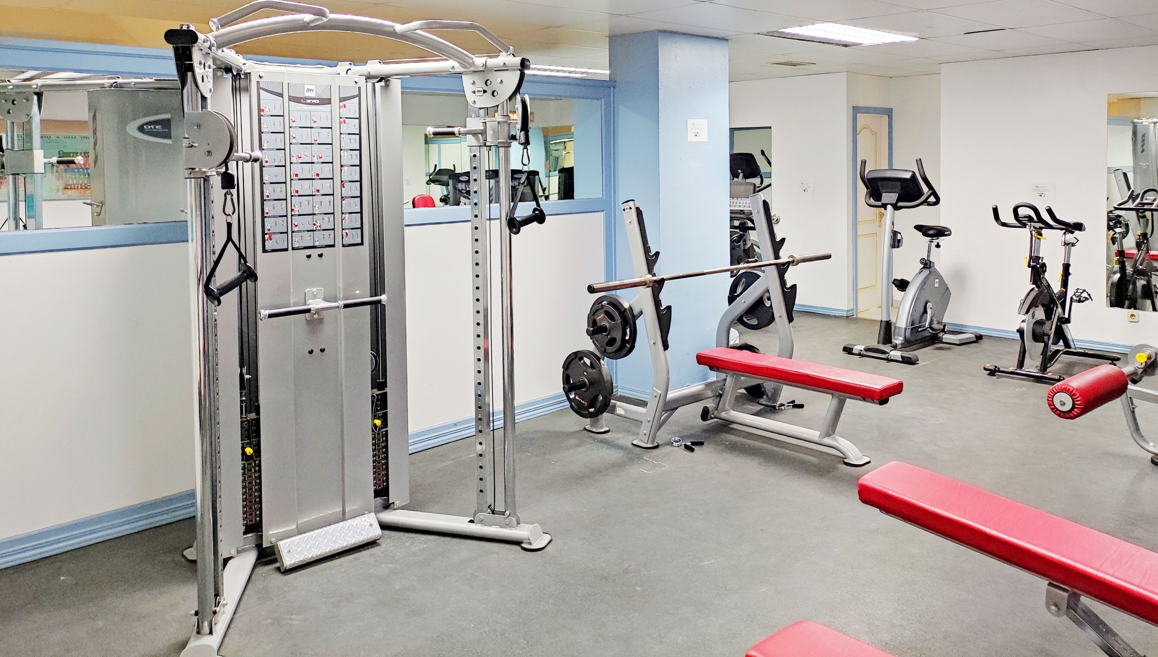 A gym with various exercise equipment, including a squat rack, bench press, and cardio machines.